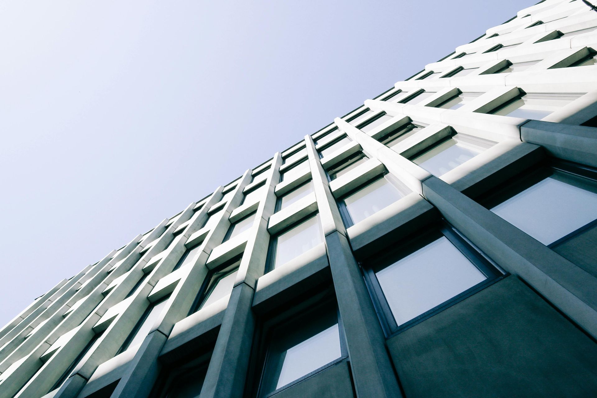 Low-angle view of a tall building with many windows against a clear blue sky.