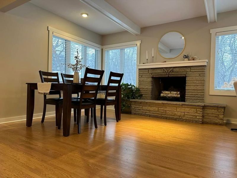 A dining room with a table and chairs and a fireplace.