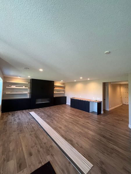 A large empty living room with hardwood floors and a fireplace.