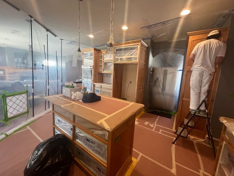 A man is painting a kitchen with a ladder.