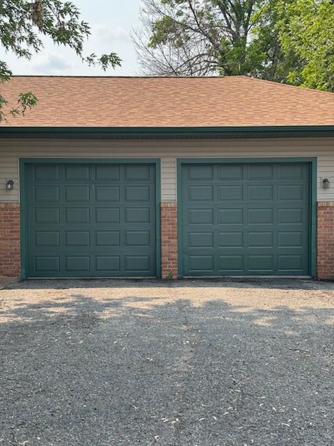 A garage with two green garage doors and a red roof