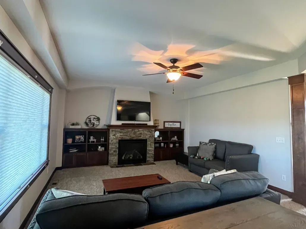 A living room with a fireplace and a ceiling fan