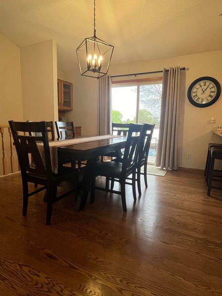 A dining room with a table and chairs and a clock on the wall.