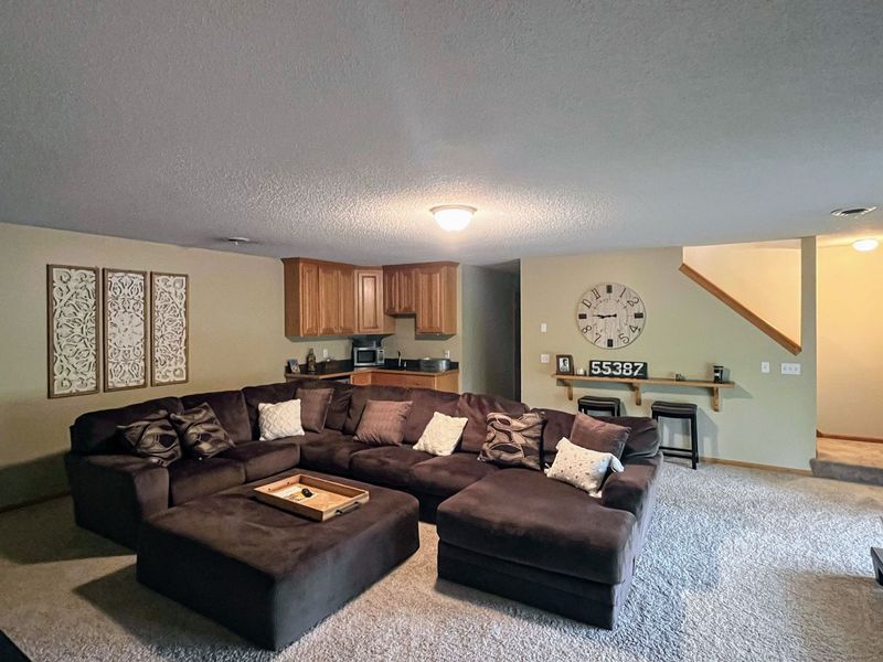 A living room with a large sectional couch and a clock on the wall