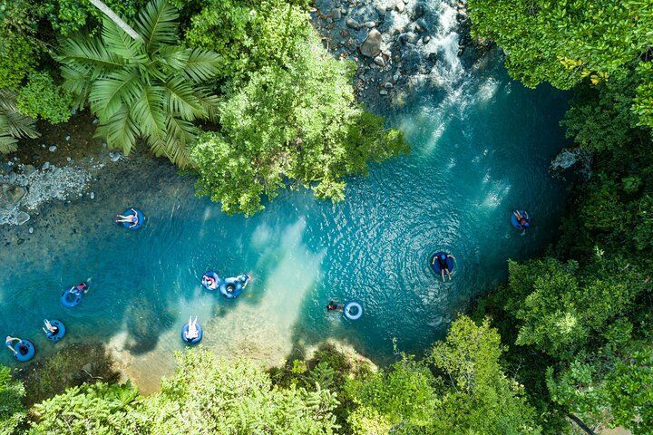 an aerial view of people floating on rafts in a river surrounded by trees .