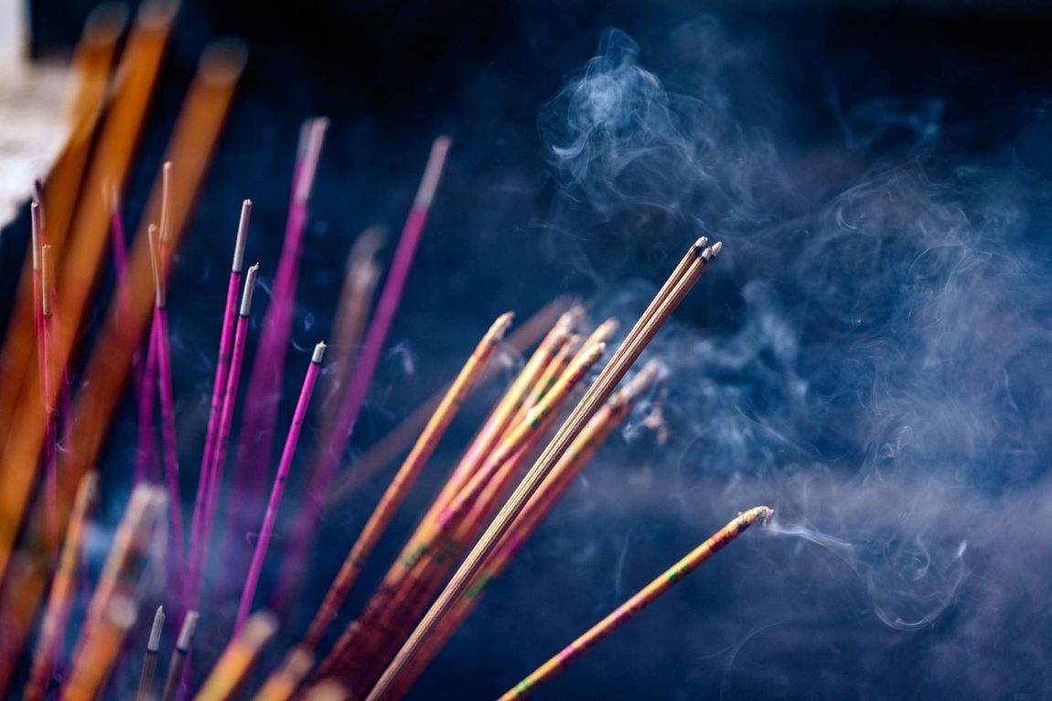 Un mazzo di bastoncini di incenso da cui esce del fumo.
