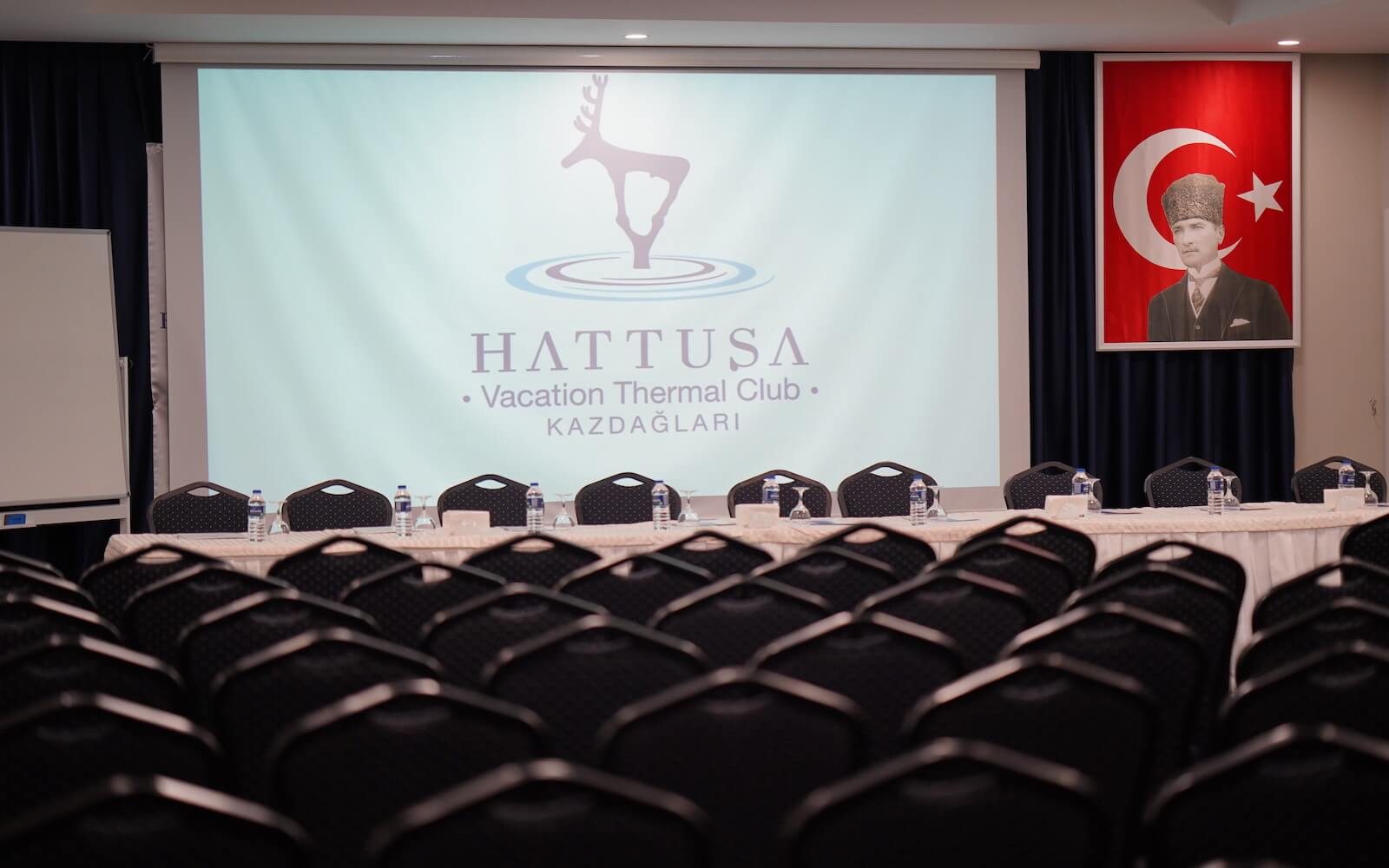 A conference room with tables and chairs and a projector screen.