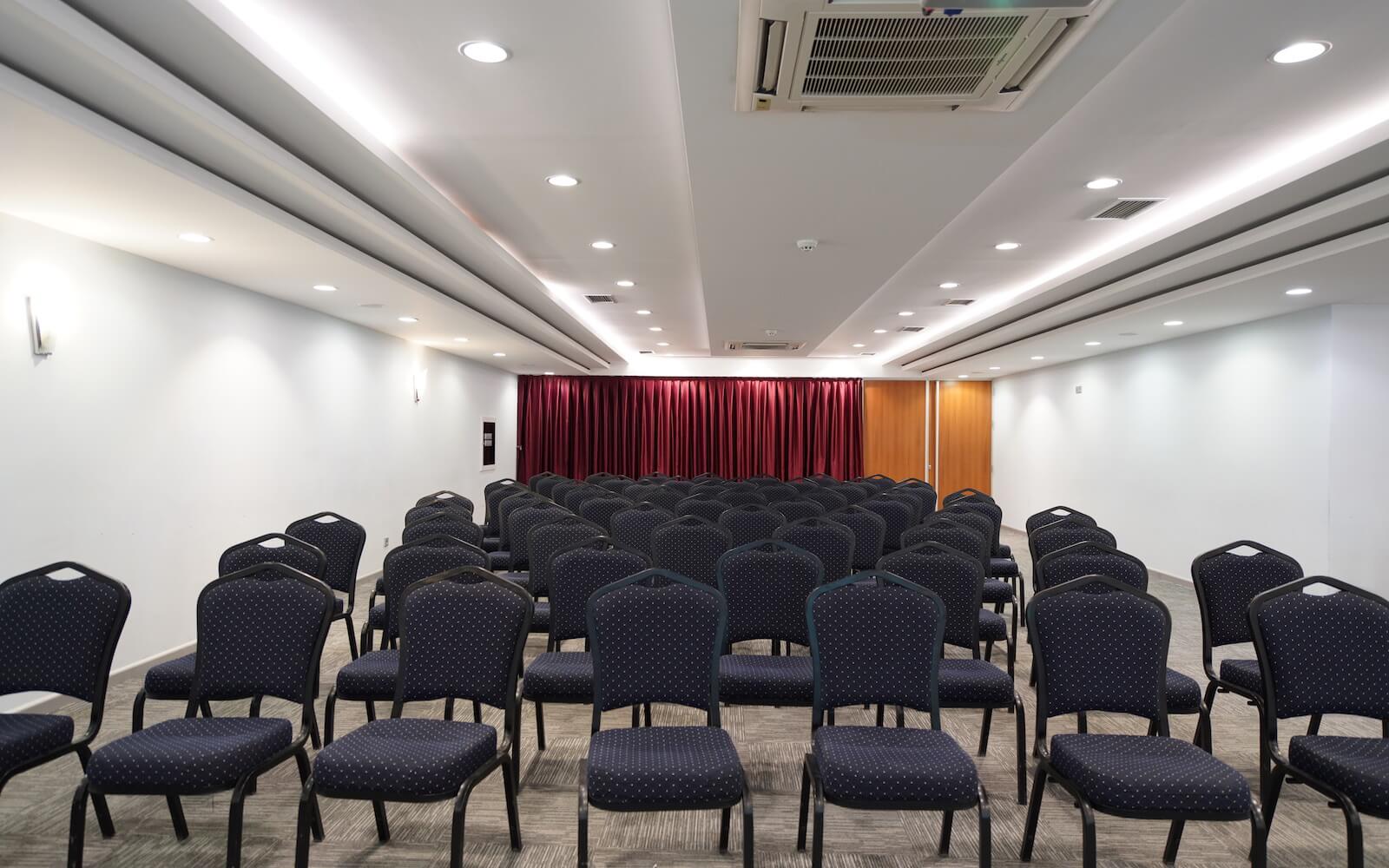 A conference room with rows of chairs and a red curtain