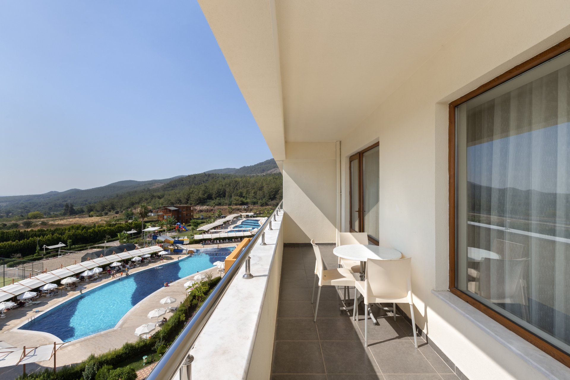 Ein Balkon mit Tisch und Stühlen mit Blick auf einen Swimmingpool
