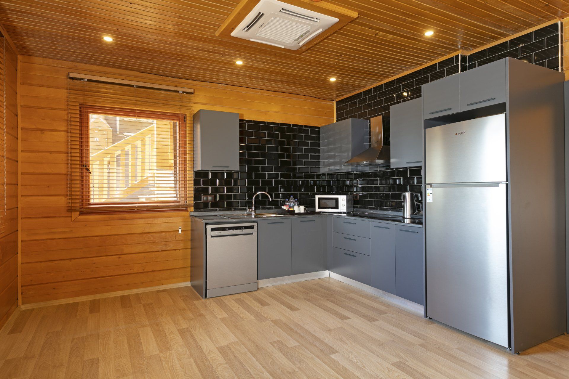 مطبخ مزود بأجهزة من الفولاذ المقاوم للصدأ وخزائن خشبية وثلاجة وغسالة أطباق.