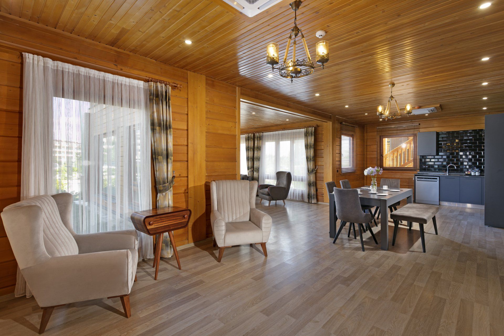 غرفة معيشة بجدران خشبية وكراسي وطاولة وثريا.