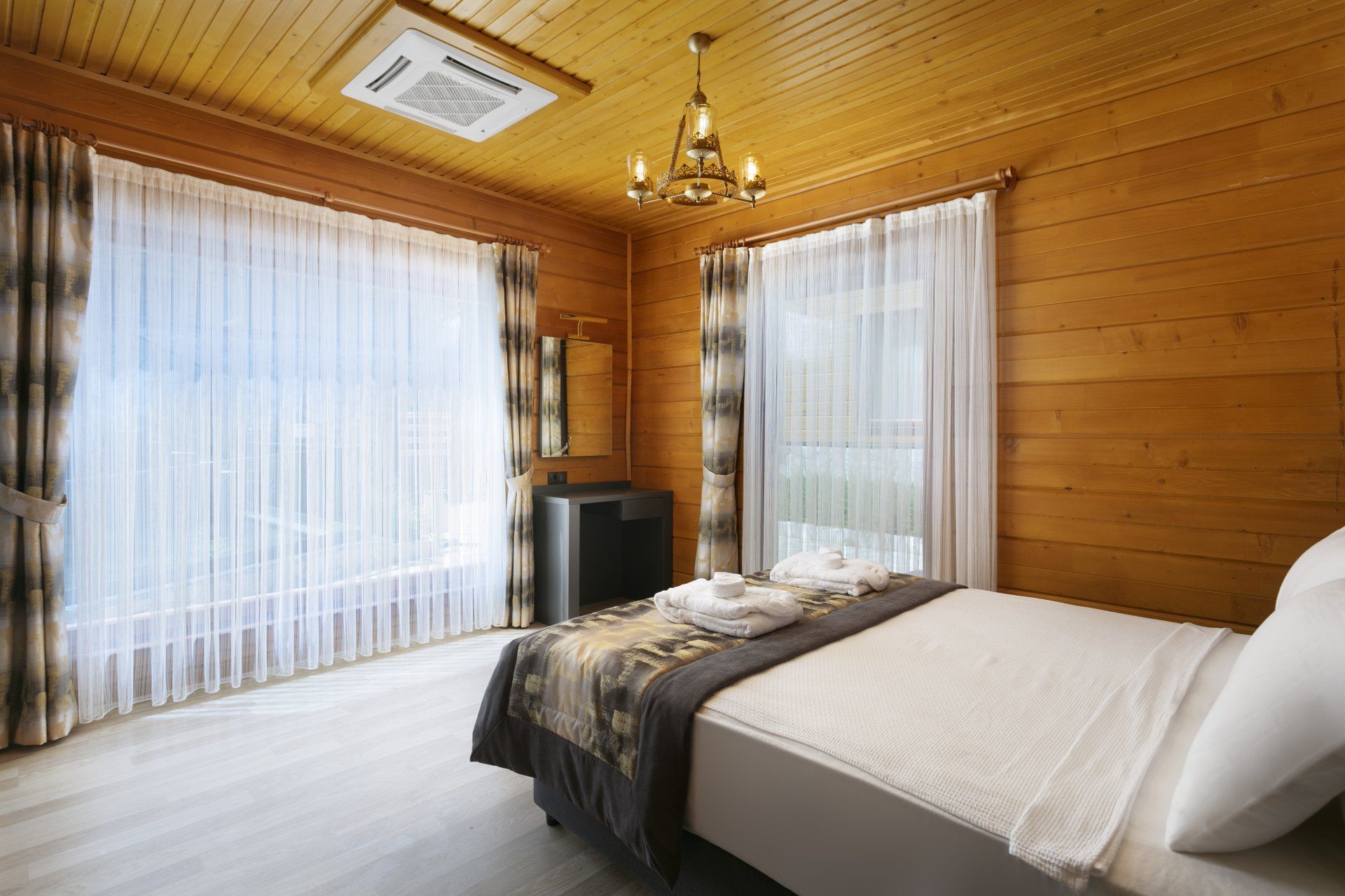 غرفة نوم في مقصورة خشبية بها سرير كبير والعديد من النوافذ.