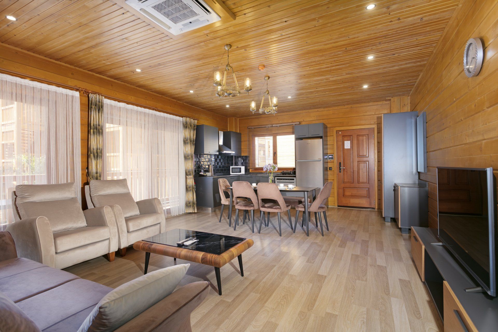 غرفة معيشة بها أريكة وكراسي وطاولة وتلفزيون.