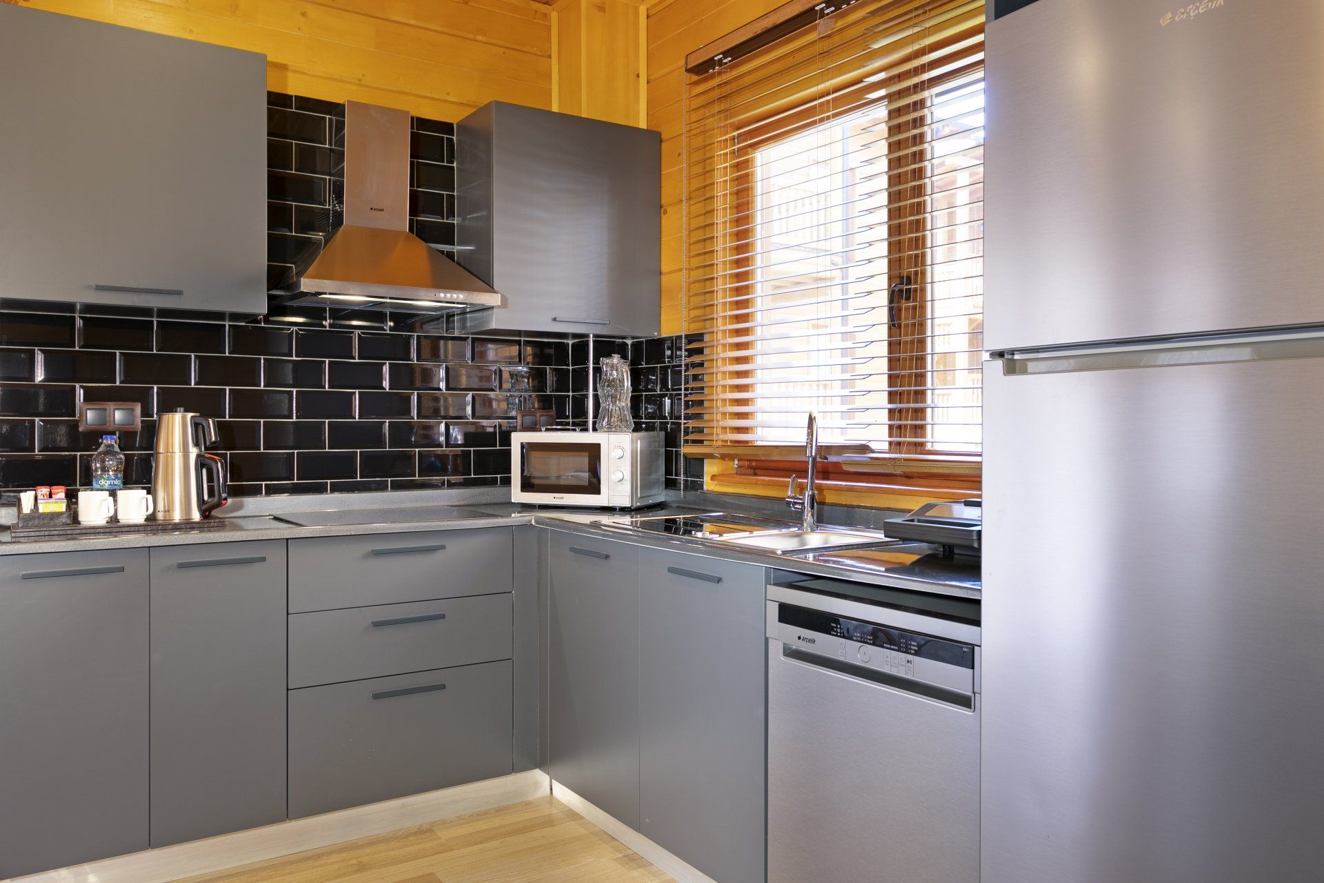 مطبخ به أجهزة من الفولاذ المقاوم للصدأ وخزائن رمادية