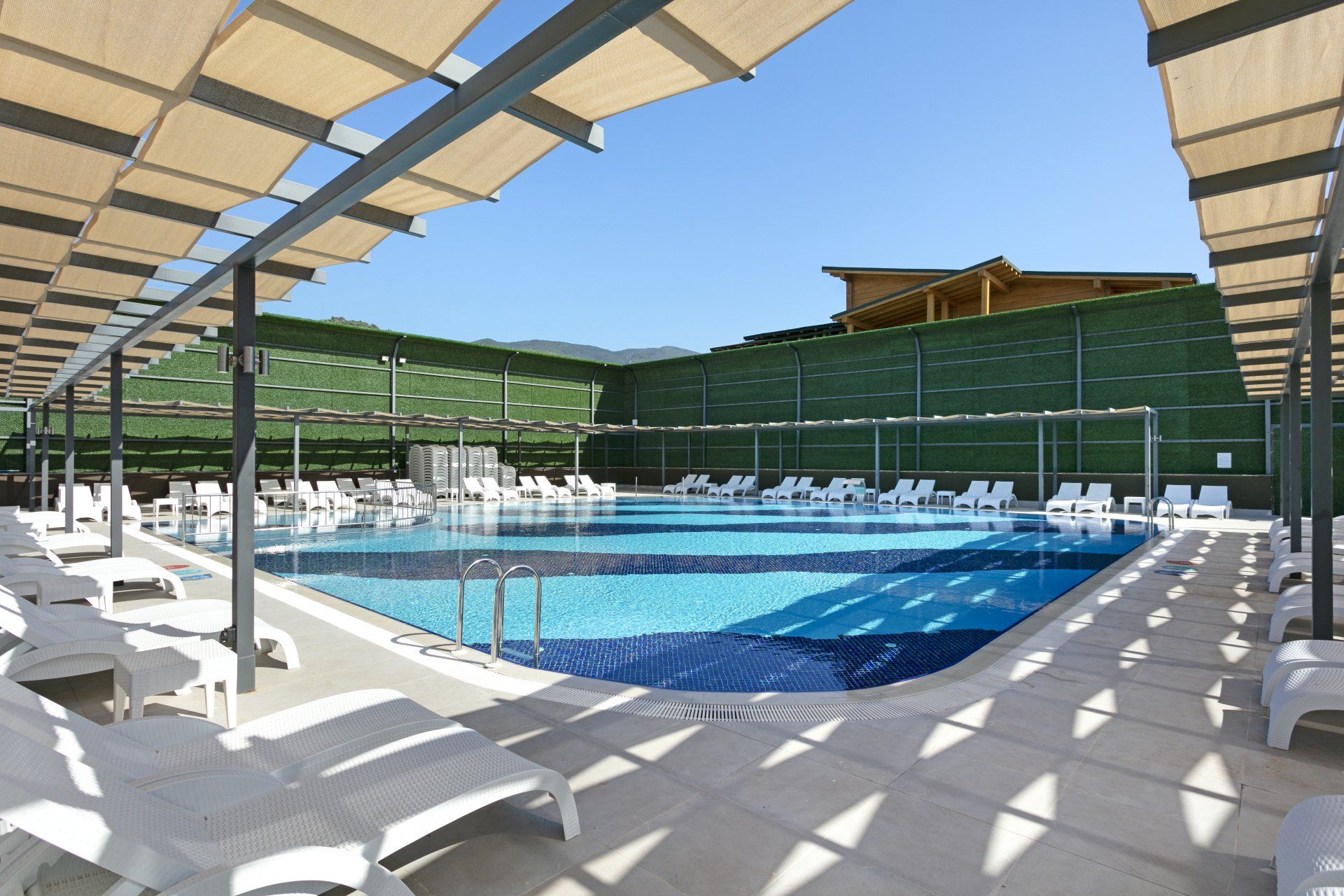 حمام سباحة كبير محاط بالكراسي والمظلات