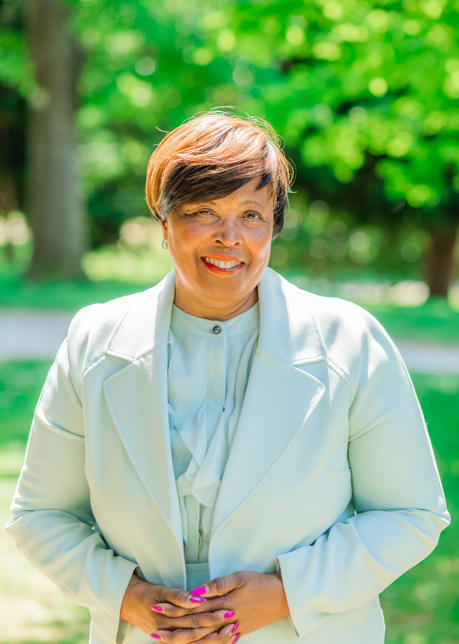 A man in a blue shirt is leaning against a wall with his arms crossed.