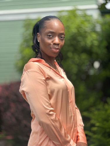A woman in a suit and polka dot shirt is smiling for the camera.