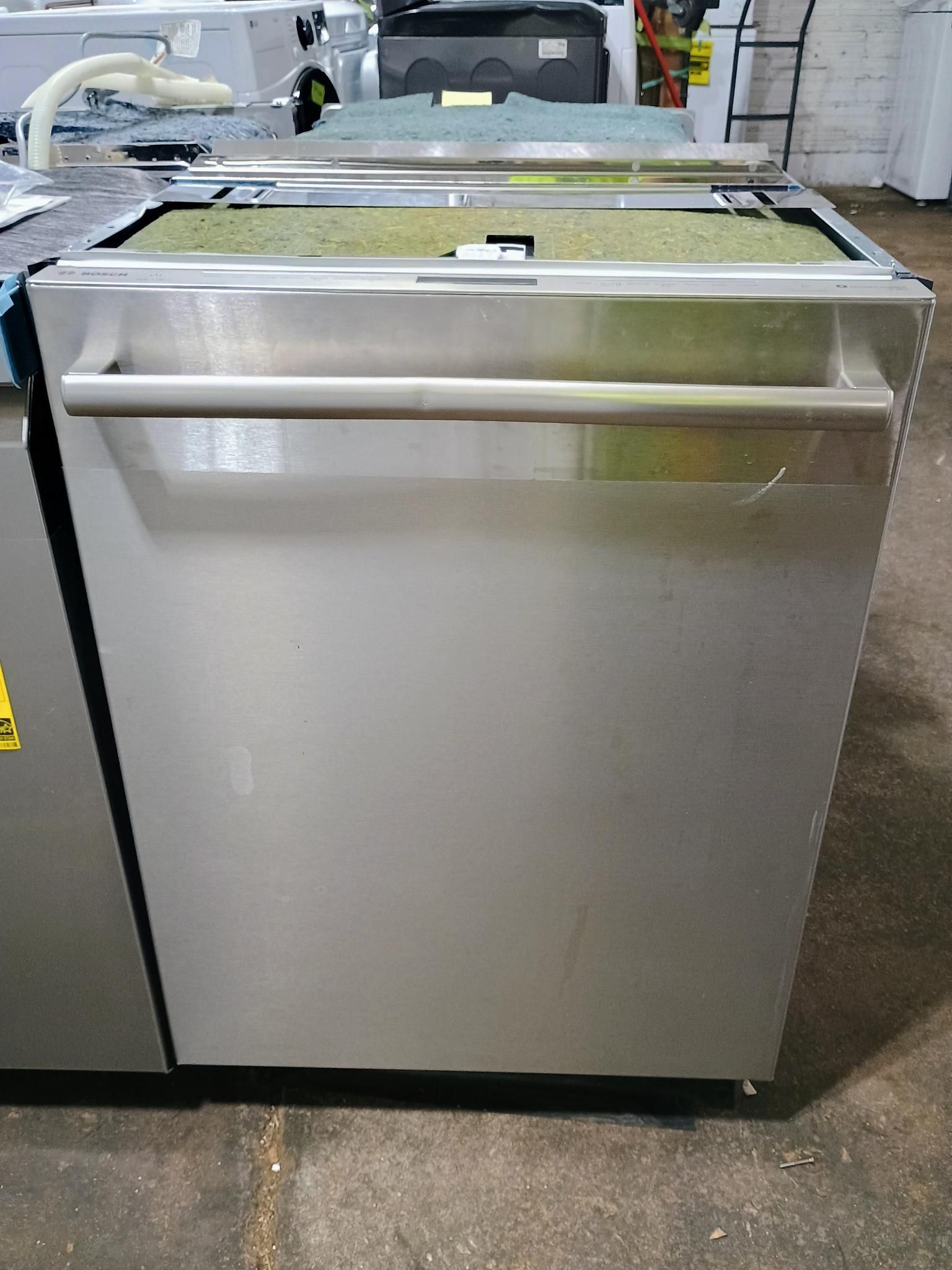 A stainless steel dishwasher is sitting on top of a concrete floor.