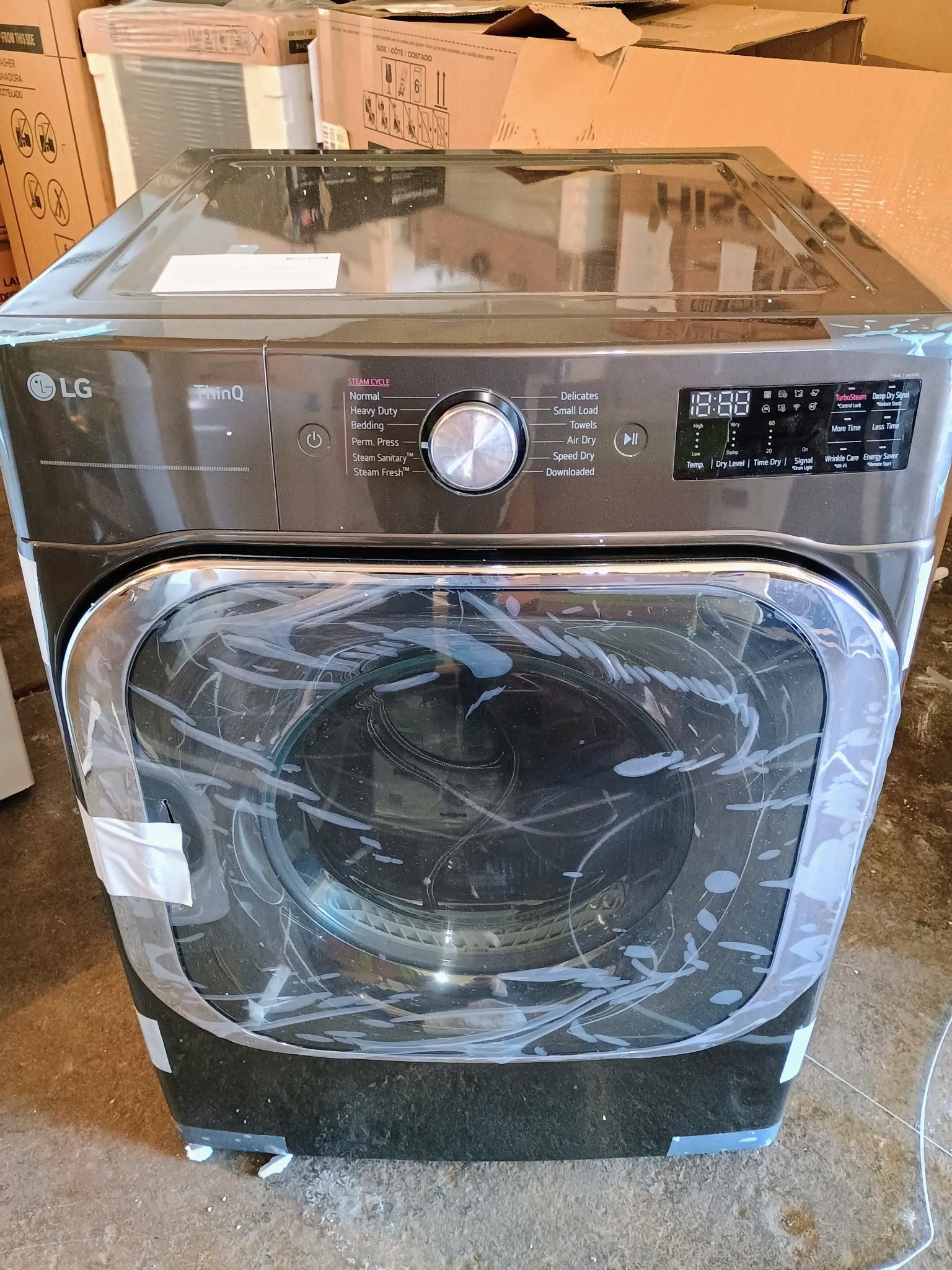 An lg washing machine is sitting on the floor in a garage.