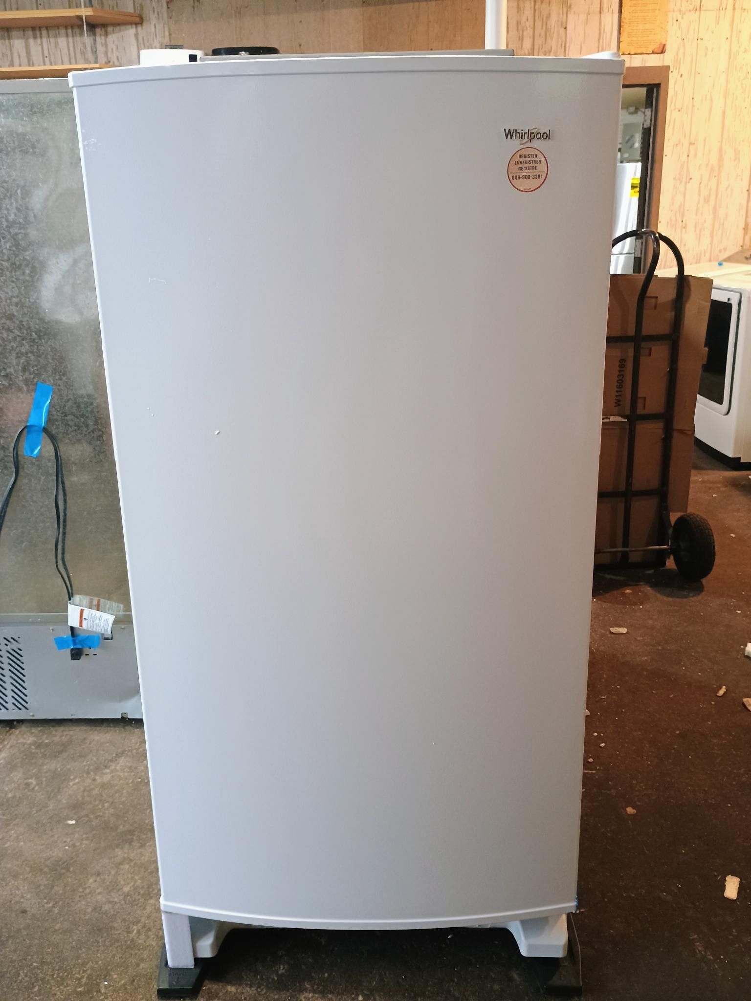 A white refrigerator is sitting in a warehouse