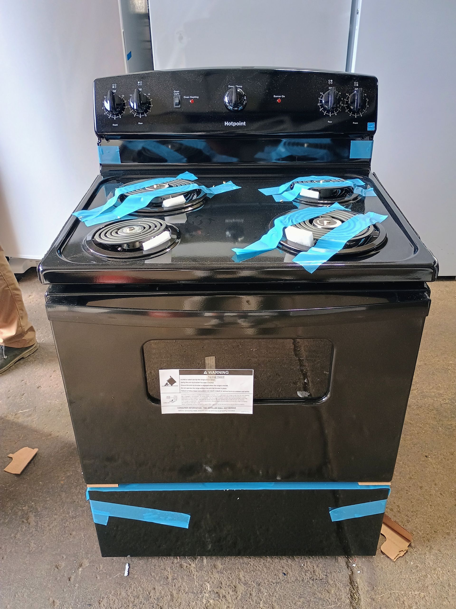 Black electric range with four burners, knobs, and oven door.