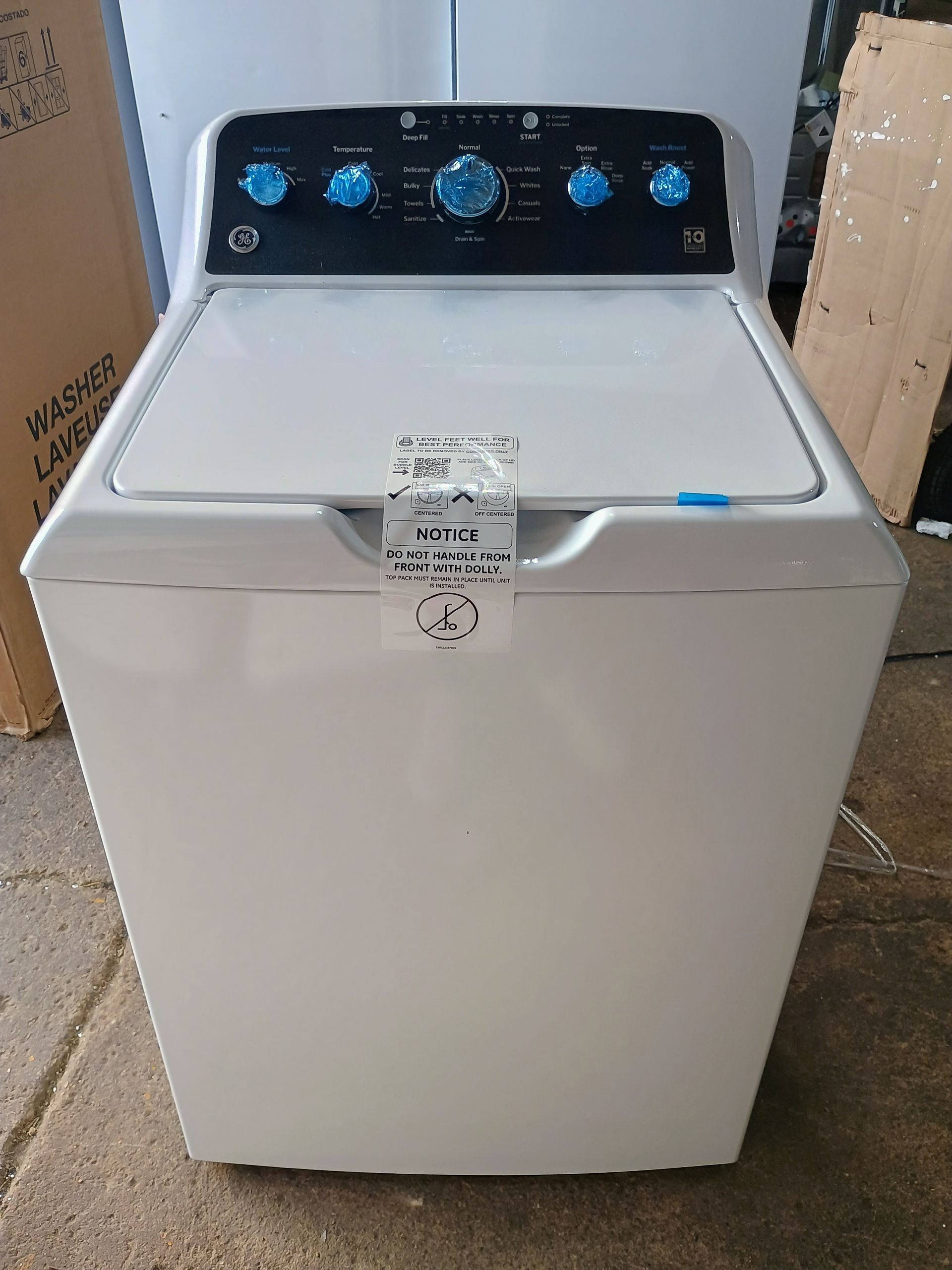 White GE top-load washing machine with black control panel and blue knobs.