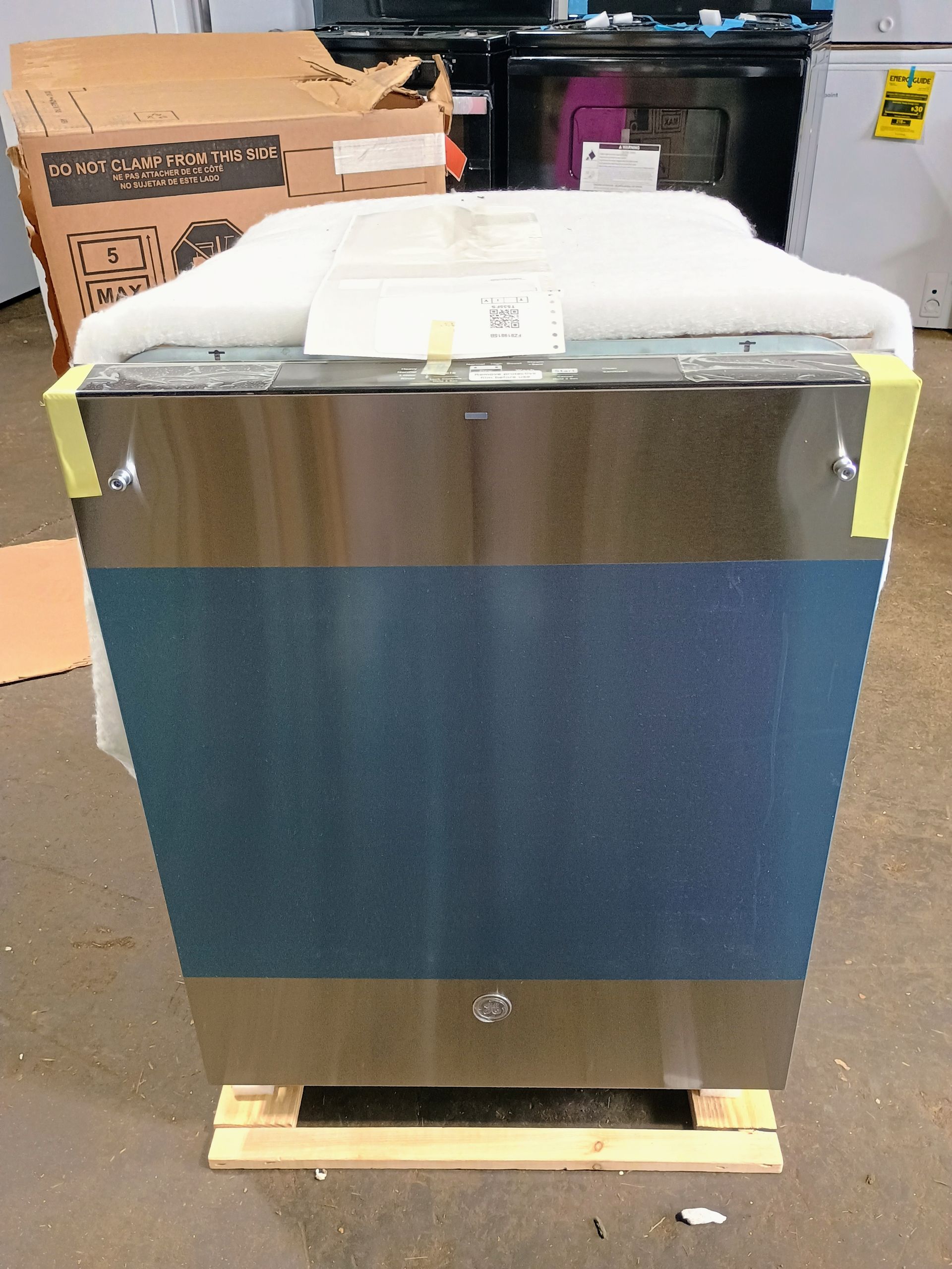 Stainless steel dishwasher on wooden pallet, wrapped in protective foam.