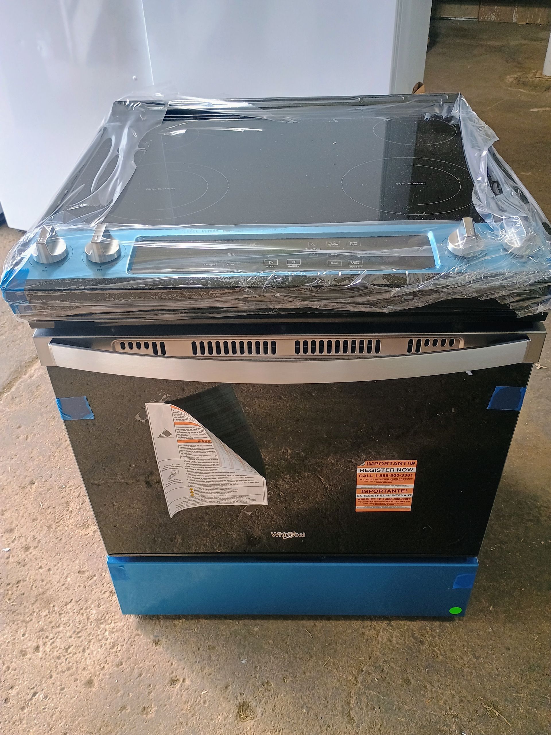 Black Whirlpool range, new, still wrapped in plastic. Controls visible on top.