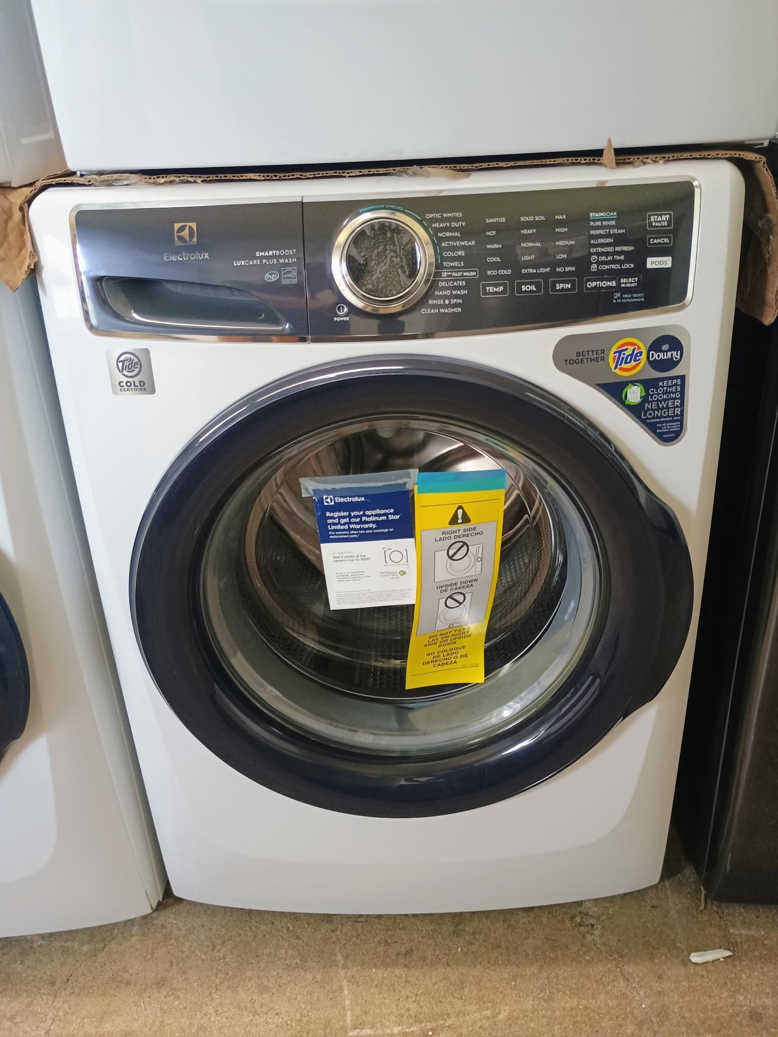 A white washing machine is sitting on top of a white washer and dryer.