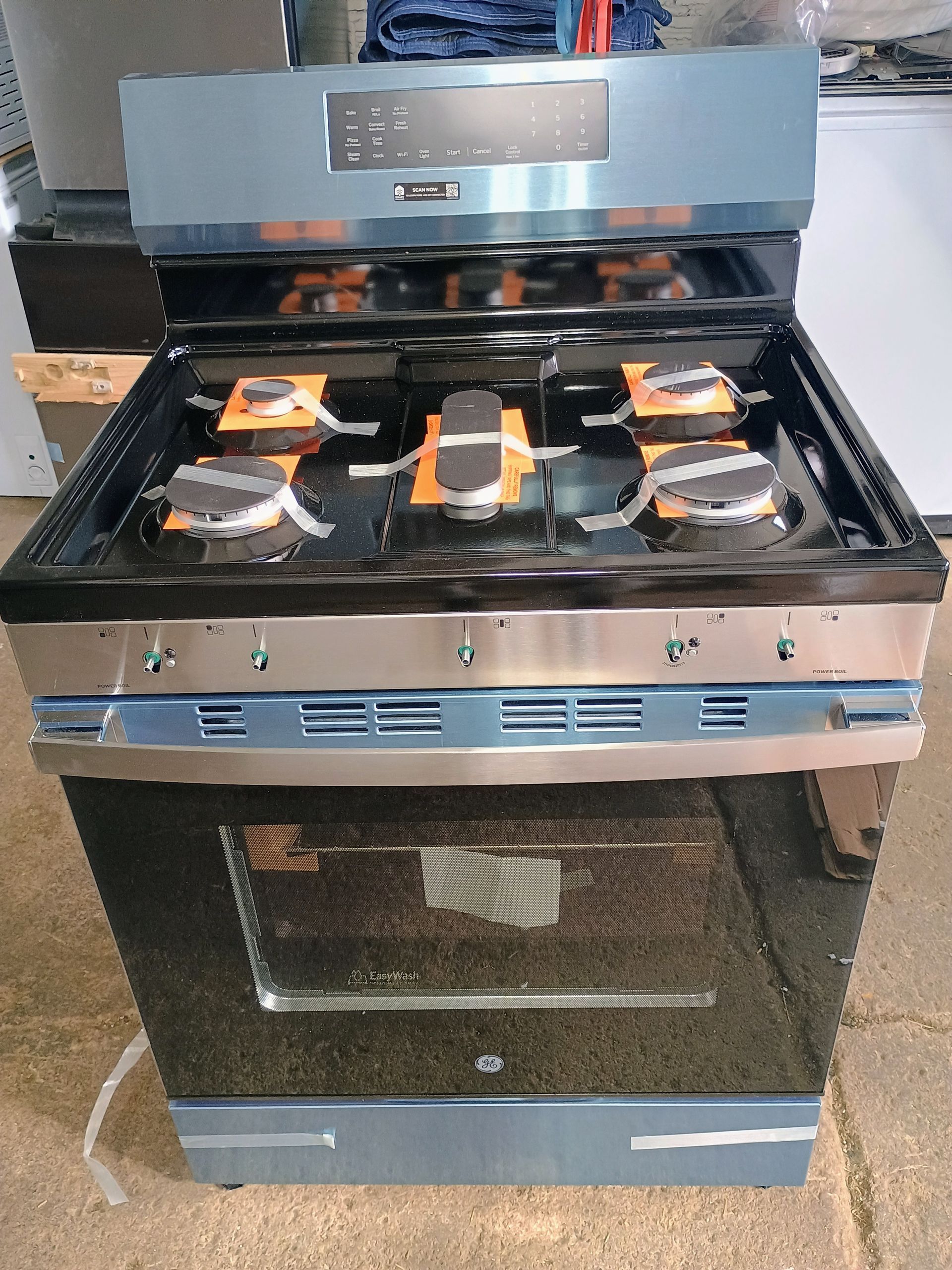 Blue and black gas range with five burners and a glass oven door.