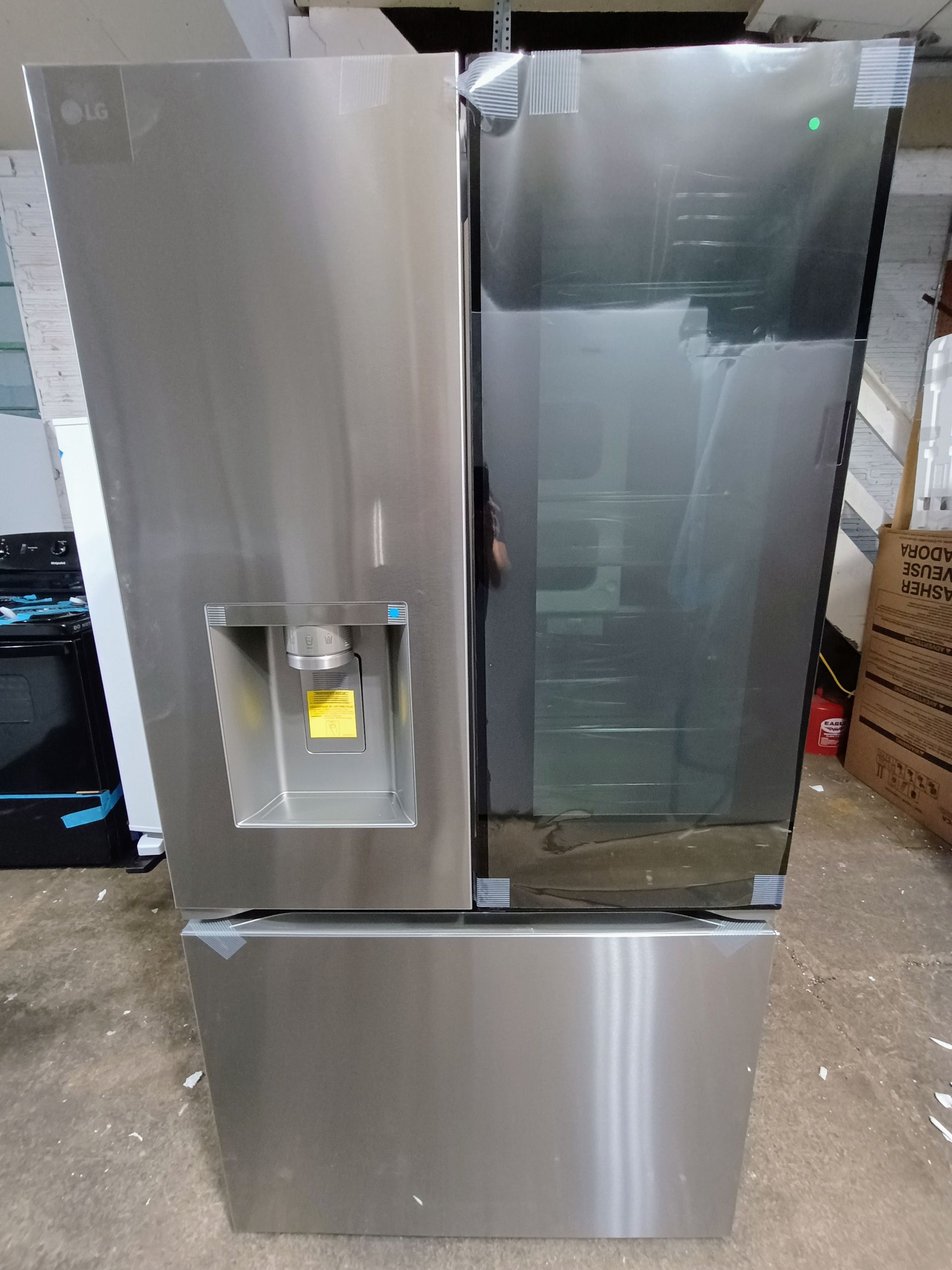 Stainless steel LG refrigerator with water dispenser and glass door.