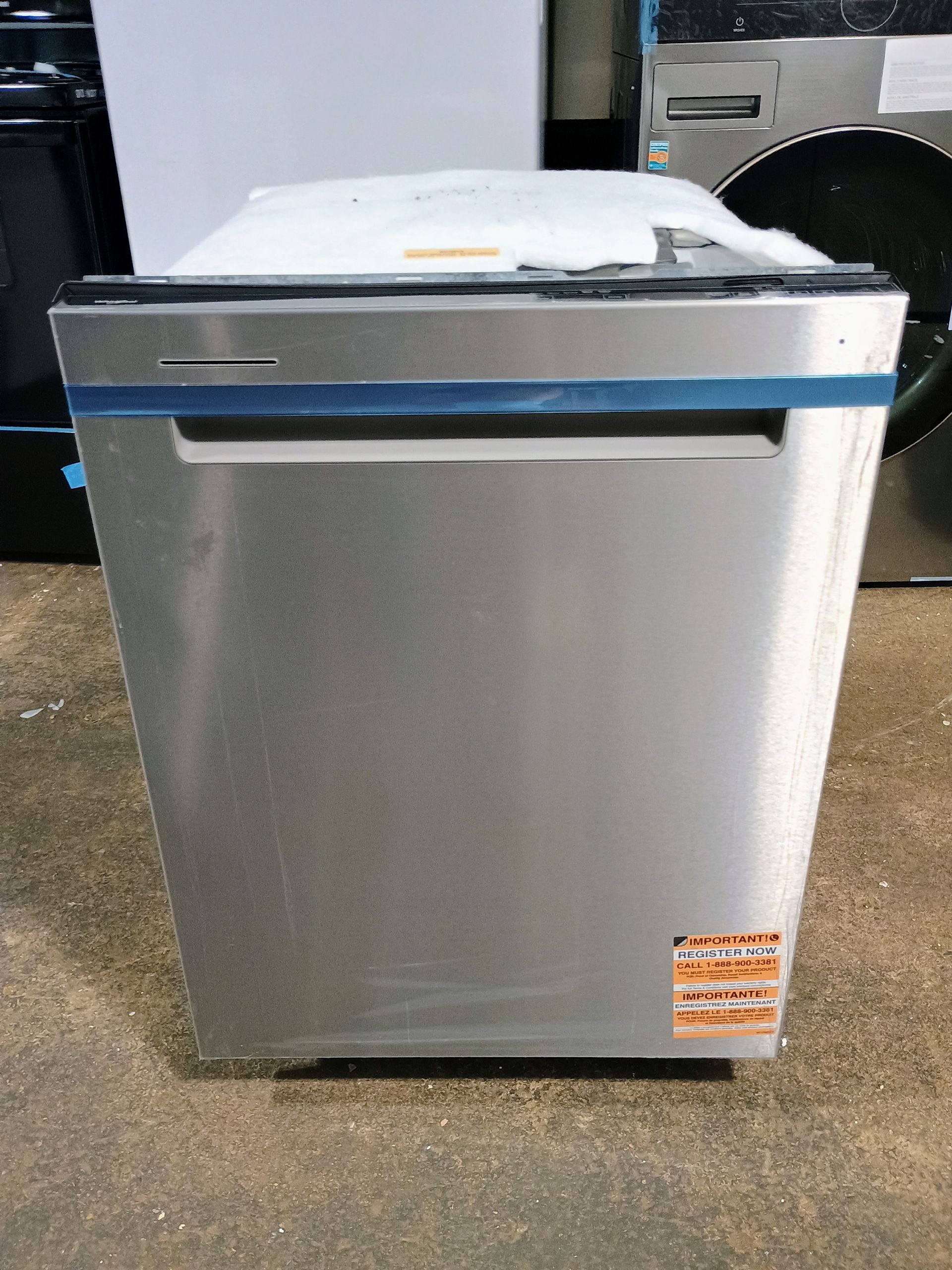 Stainless steel dishwasher with blue tape around the door, indoors.