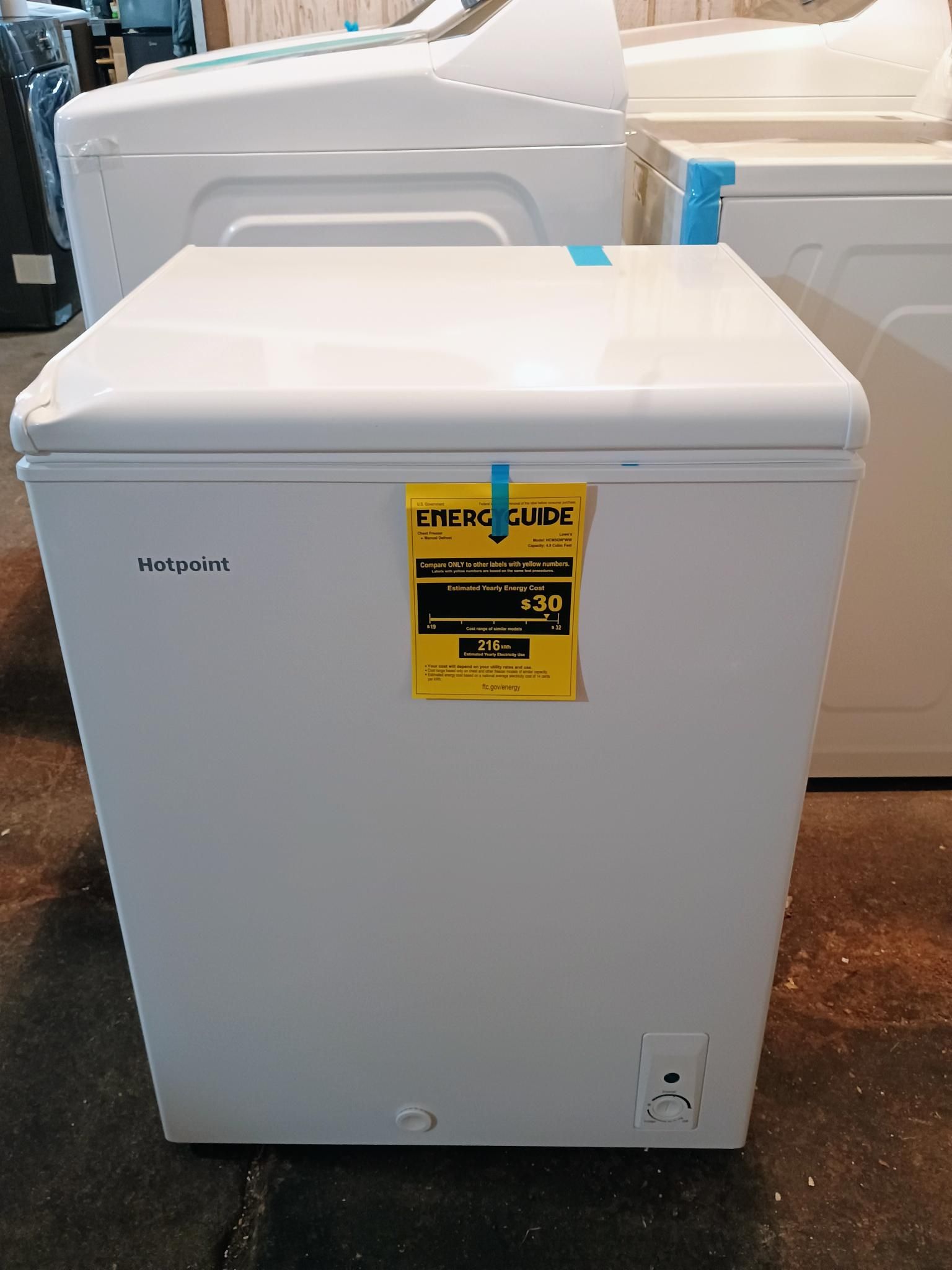 A white chest freezer with a yellow sticker on it