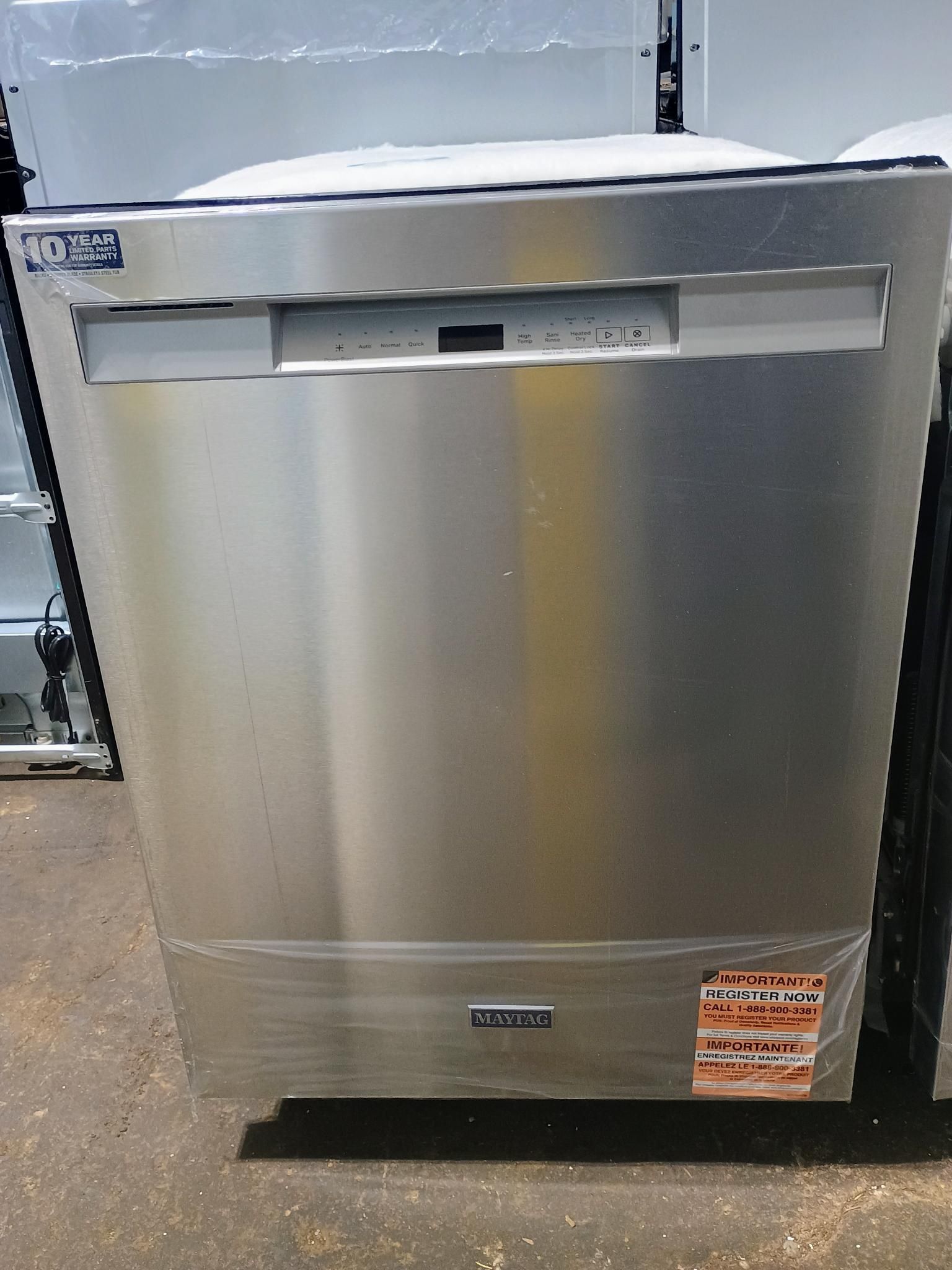 A stainless steel dishwasher is sitting on a concrete floor.