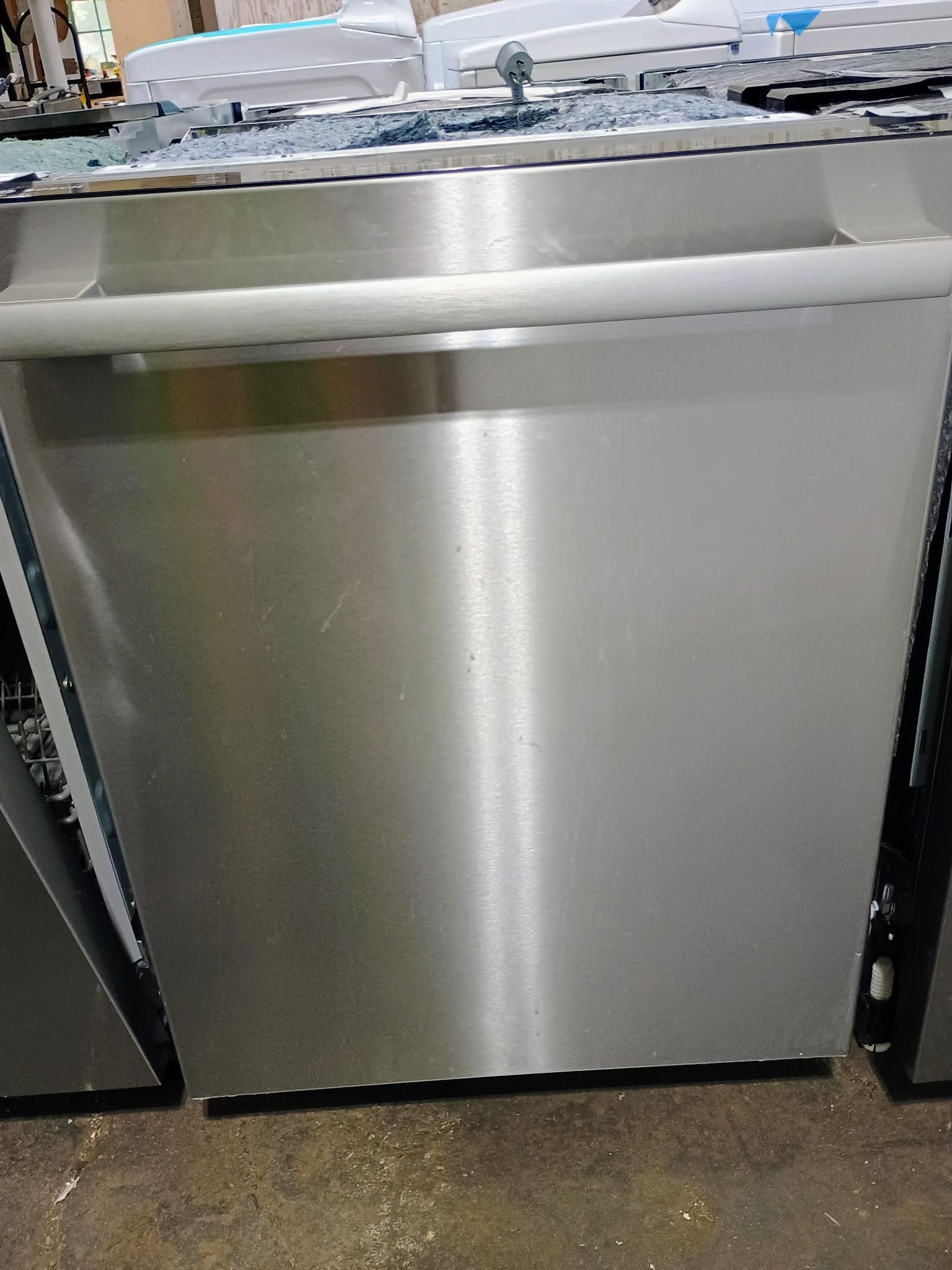 A stainless steel dishwasher is sitting on a concrete floor.