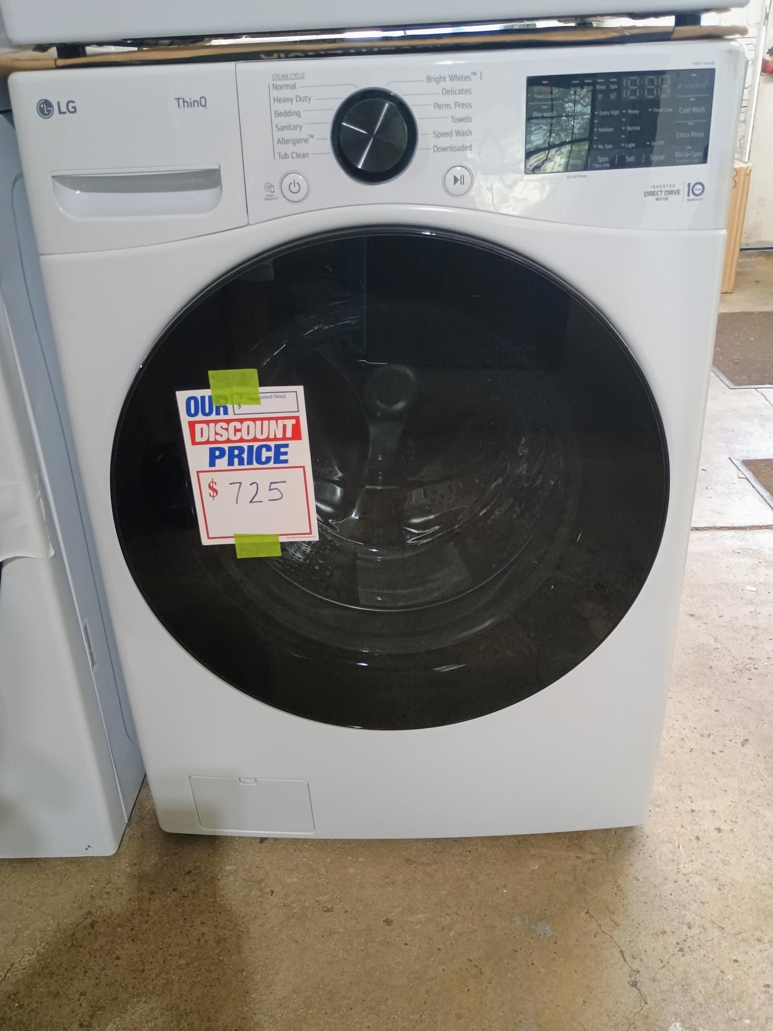 White LG washing machine with a black door, price tag on it.