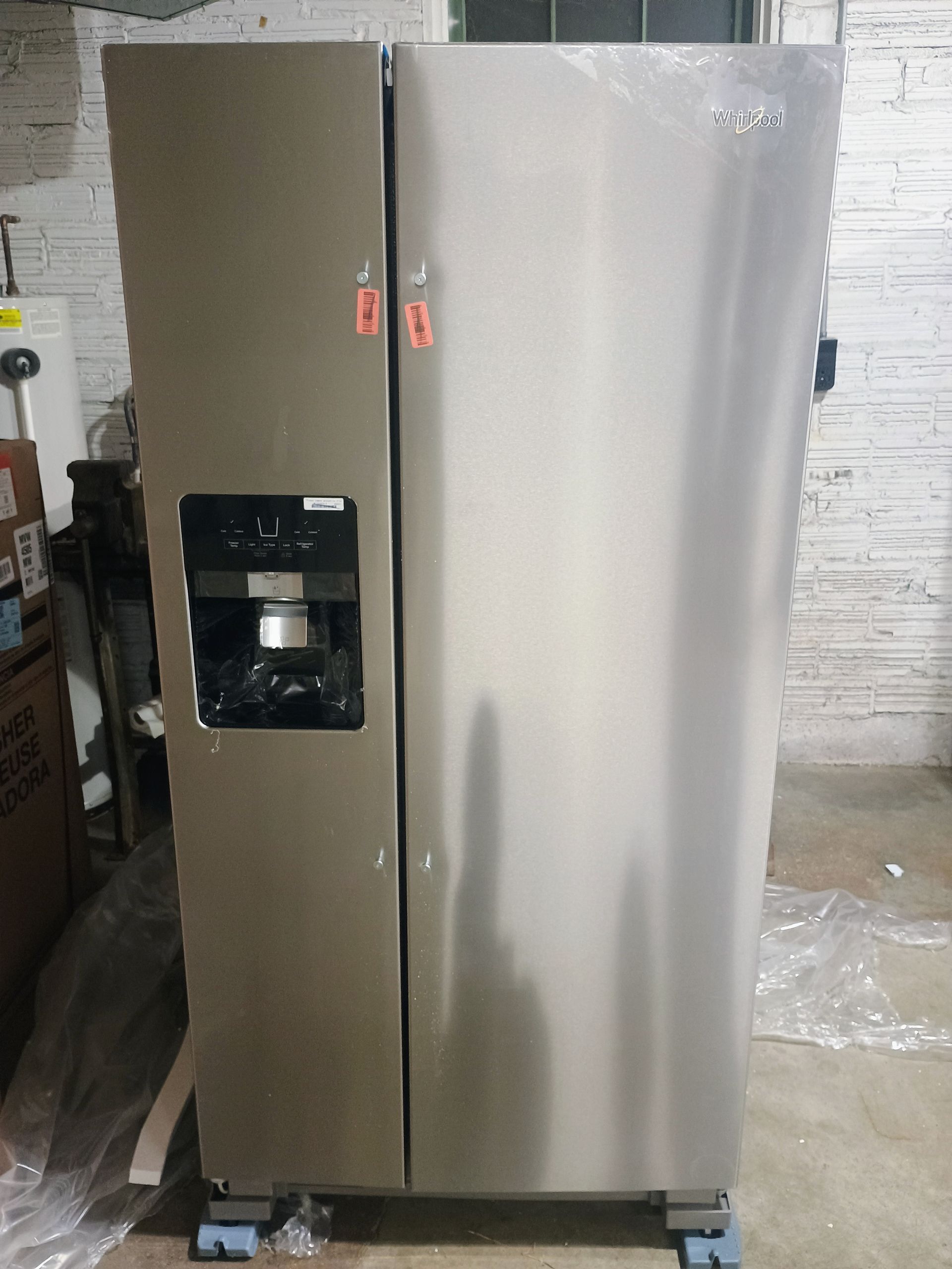 Stainless steel side-by-side refrigerator in a room. It has a water dispenser on the door.