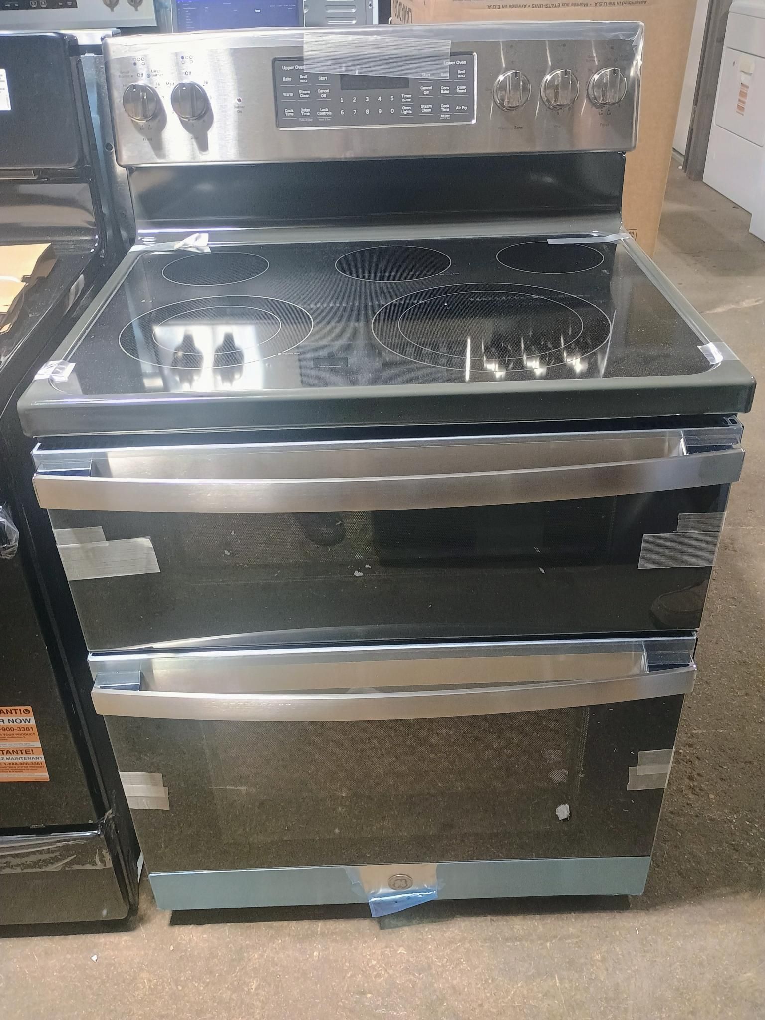 Stainless steel double oven range with glass stovetop and control panel.