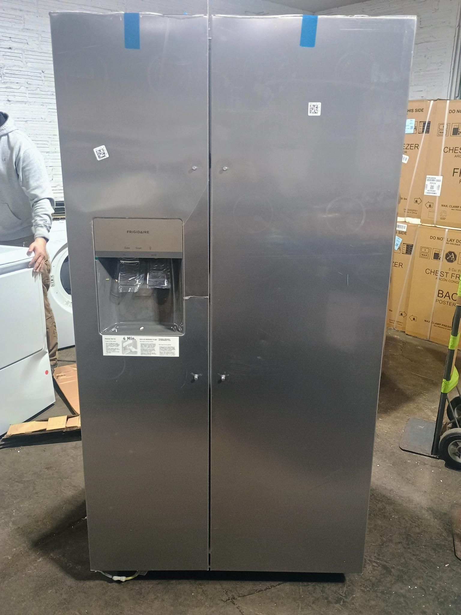 Stainless steel side-by-side refrigerator with water/ice dispenser, indoors.