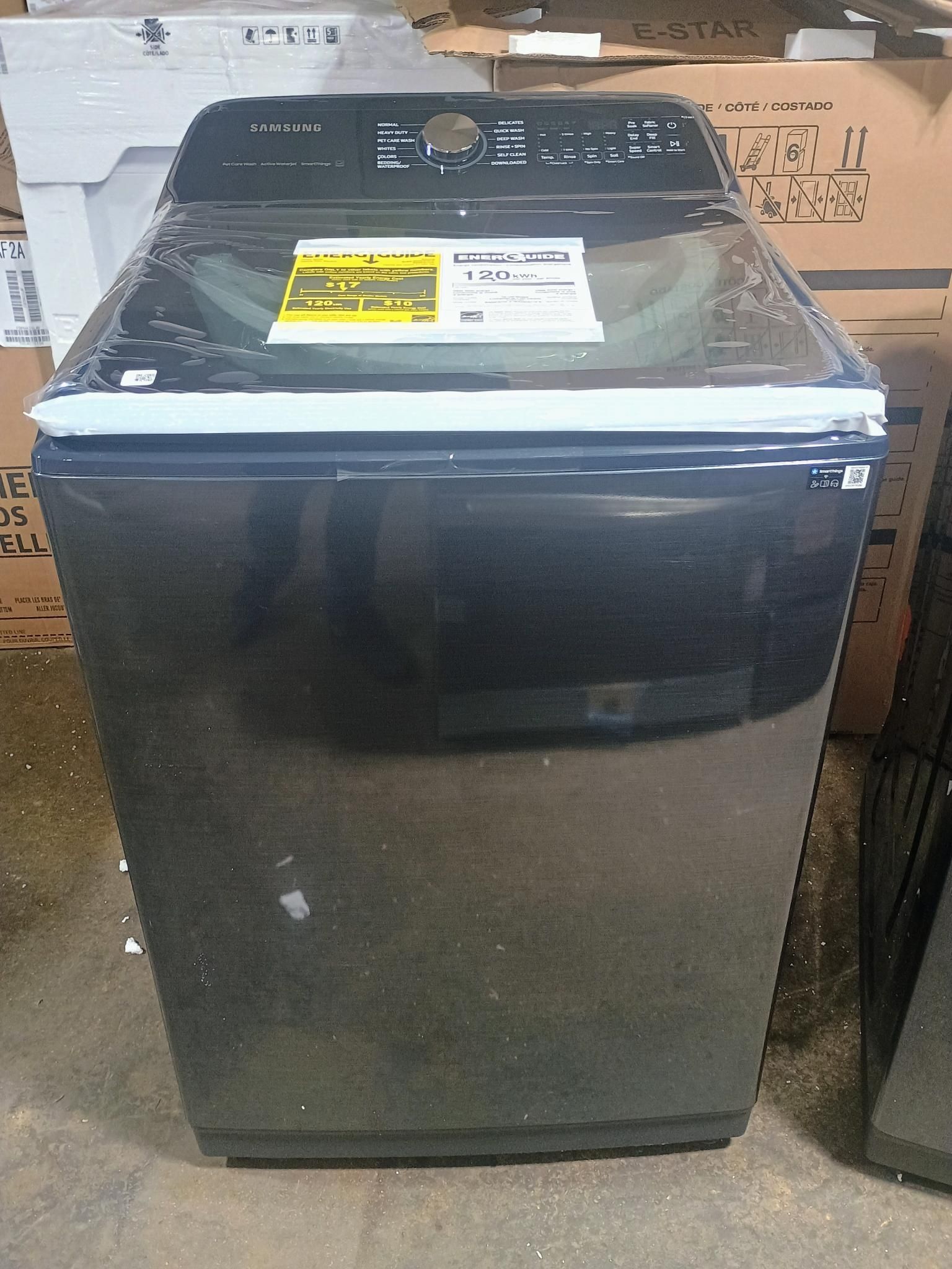 Black top-load washing machine with control panel and price tags.