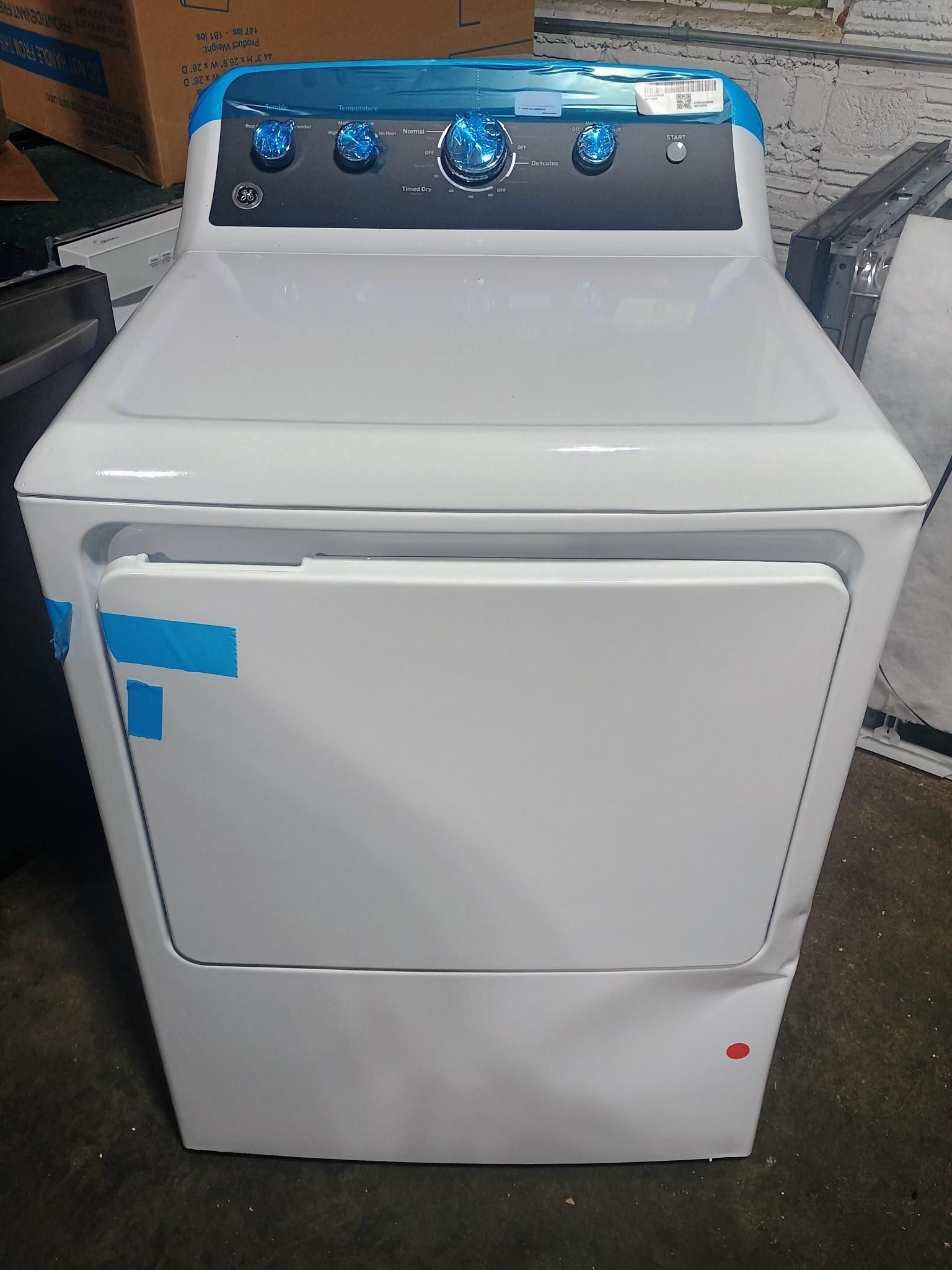 White dryer with blue controls, in an indoor setting.