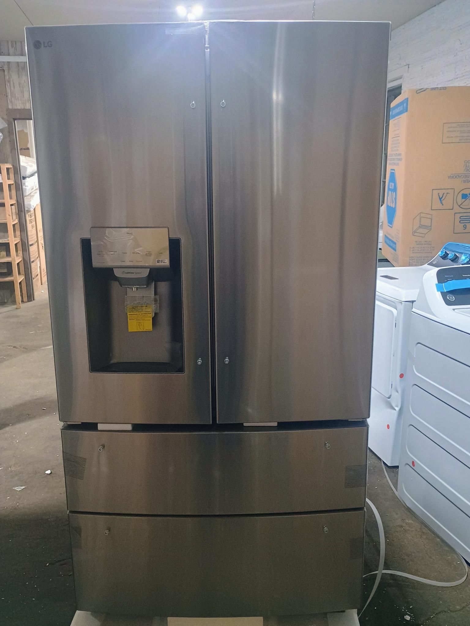 Stainless steel LG refrigerator with two doors and bottom freezer drawers; water dispenser.