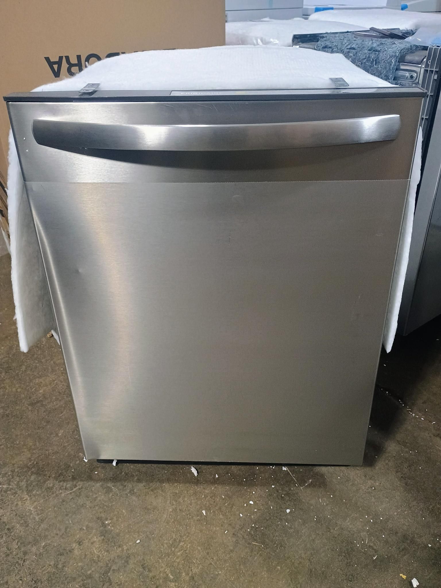Stainless steel dishwasher with a horizontal handle, inside a storage area.
