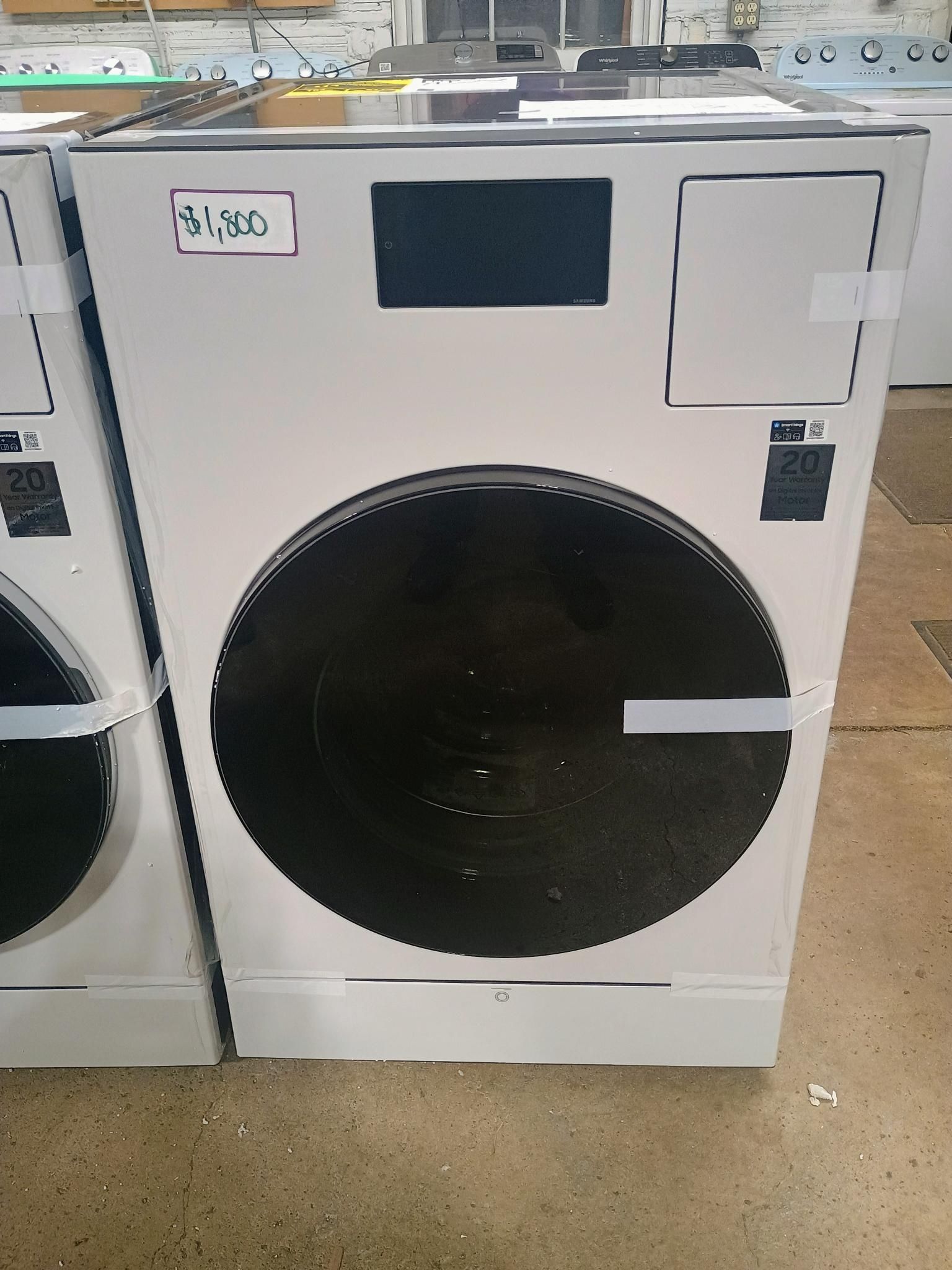 White commercial clothes dryer with a large, black opening.