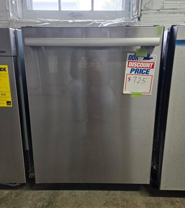 A stainless steel dishwasher is sitting on a concrete floor.