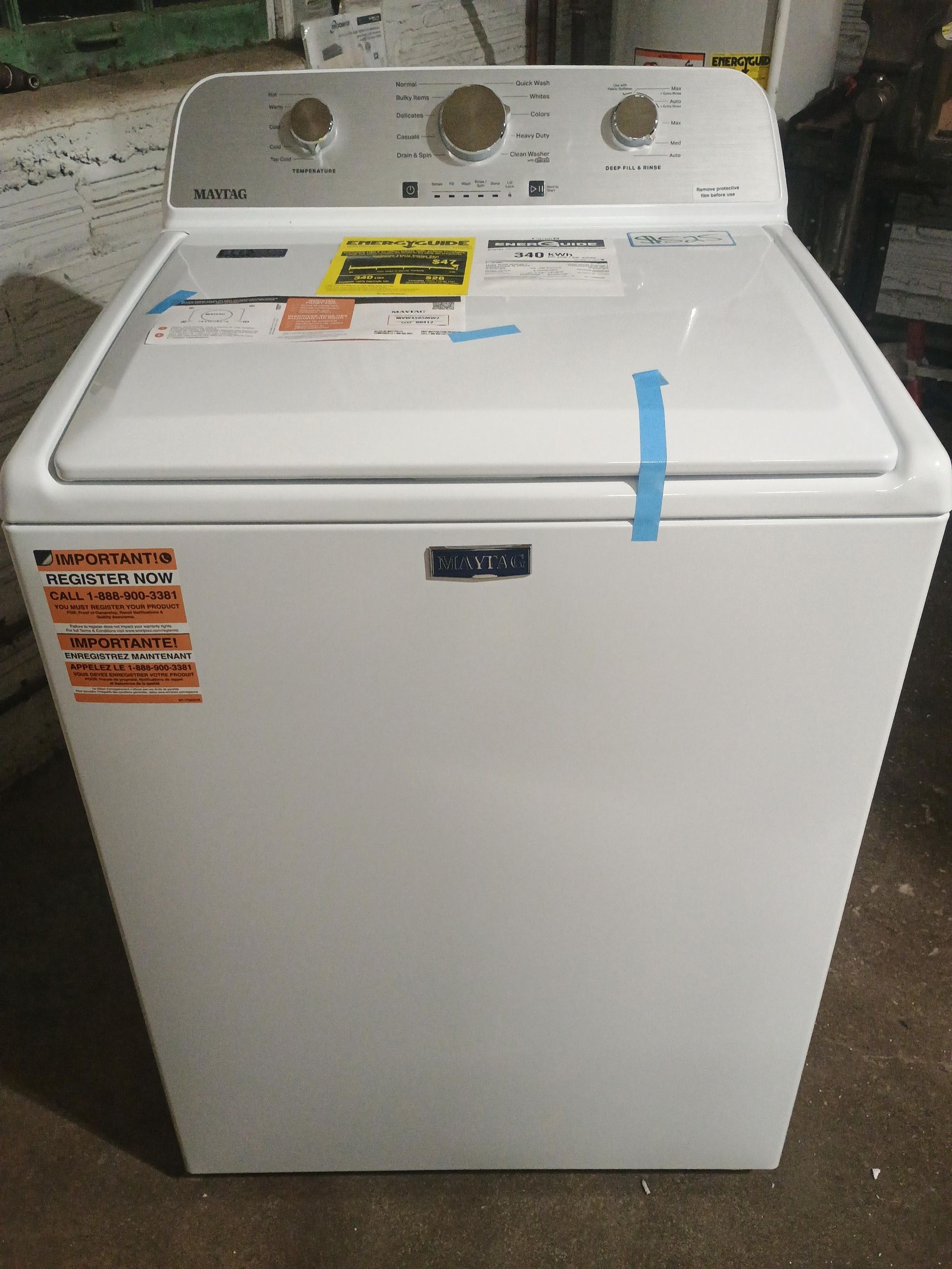 White Maytag top-load washing machine with control panel and energy guide sticker on top.