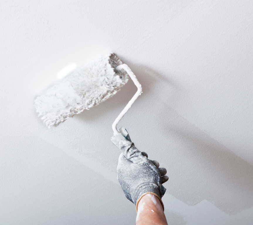 A person is painting a ceiling with a paint roller.