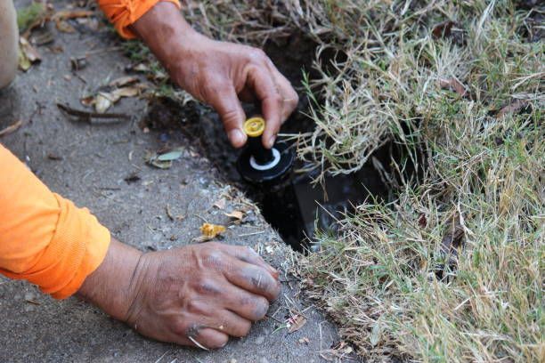 Close-up of a lawn sprinkler system contractor's hands installing a new sprinkler head.