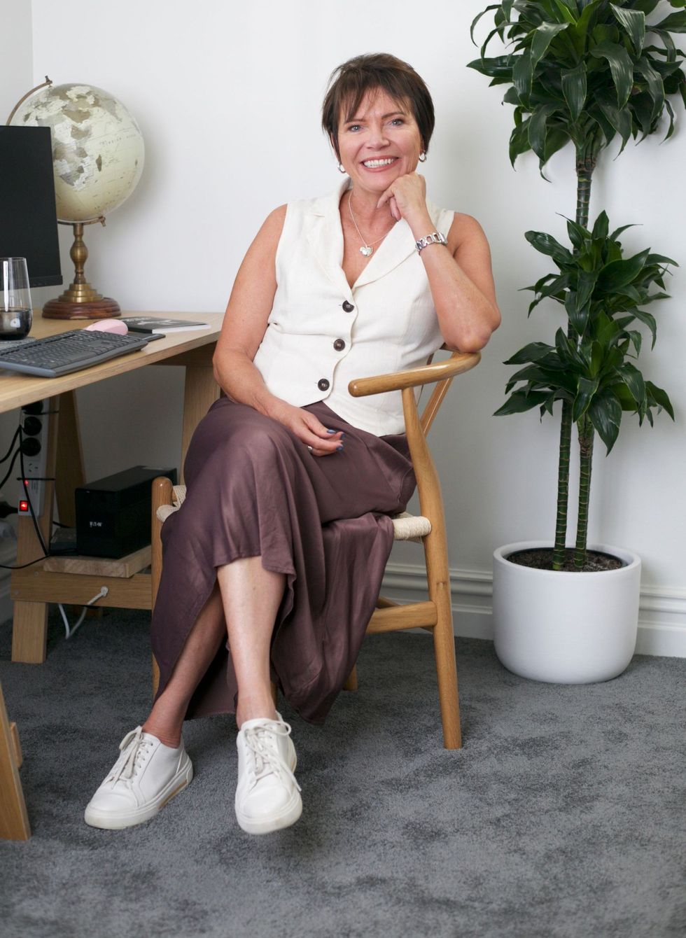 Corinne is sitting in a chair in front of a computer desk.