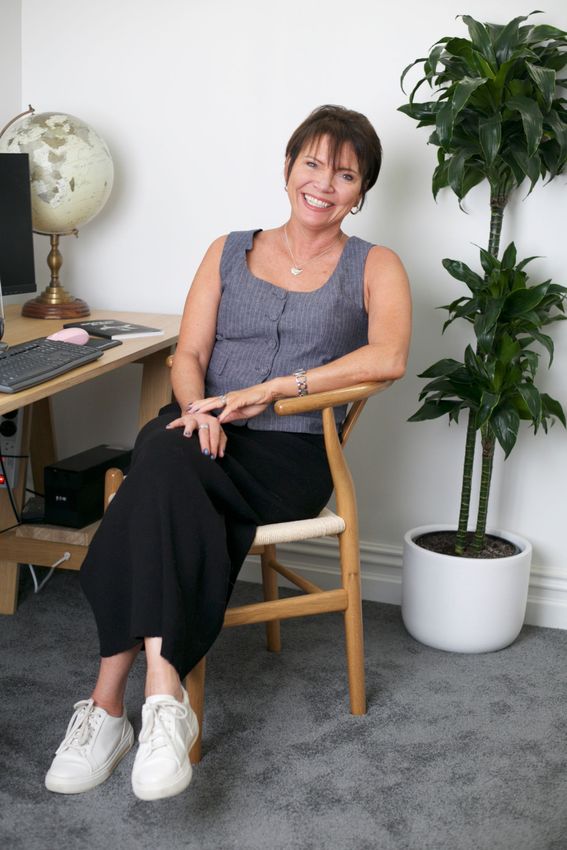 Corinne is sitting in a chair in front of a computer desk.